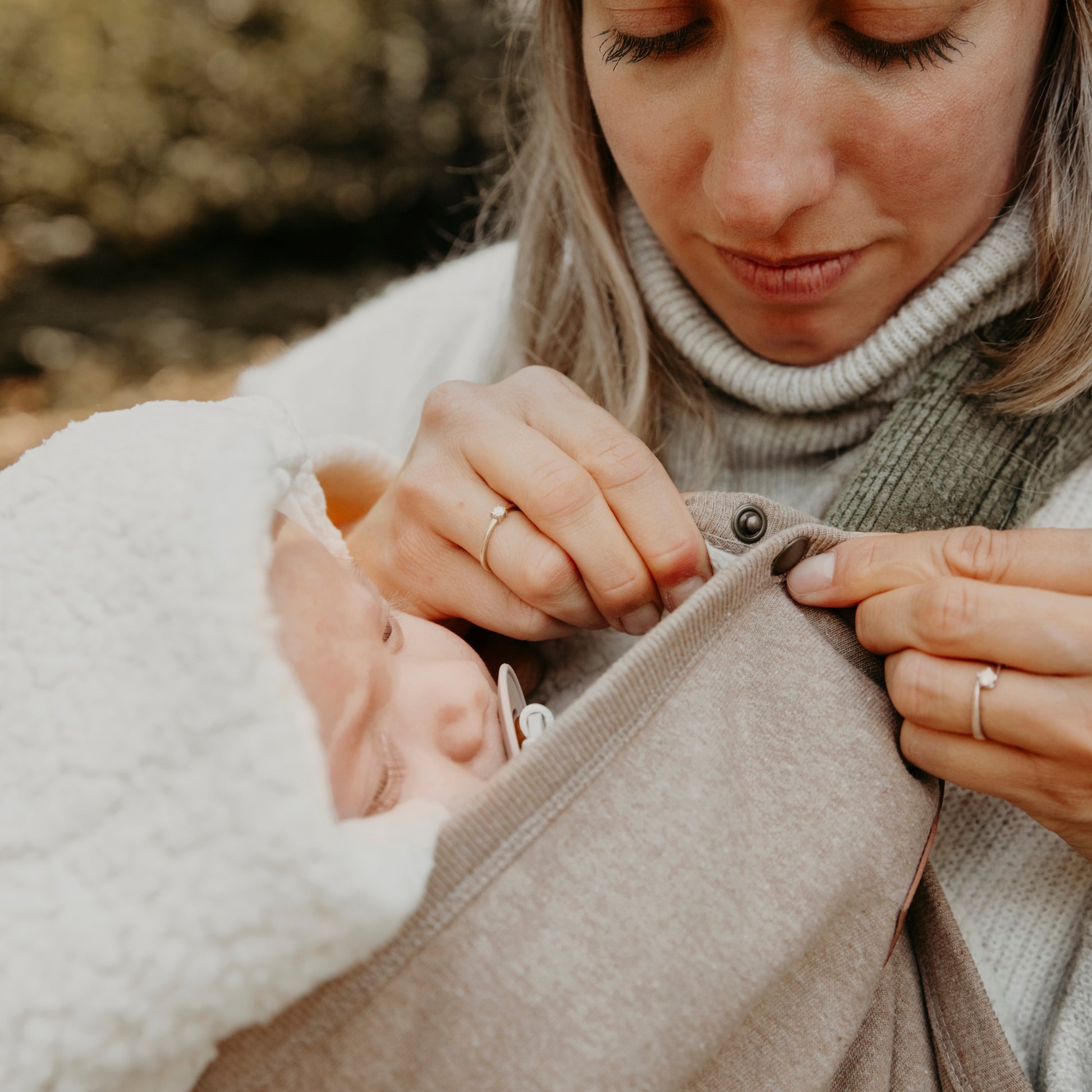 Drukknoopjes op bruine babydeken over draagzak